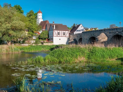 View across the Wörnitz river to the old town with the medieval stone bridge and church, Harburg,