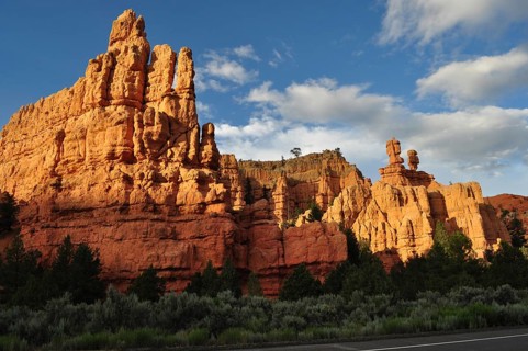 Massive red rock formations in sunlight under a blue sky with clouds, Bryce Canyon National Park,
