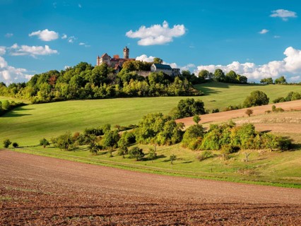 Field landscape in Wetterau in summer under blue sky with cumulus clouds, Ronneburg in the