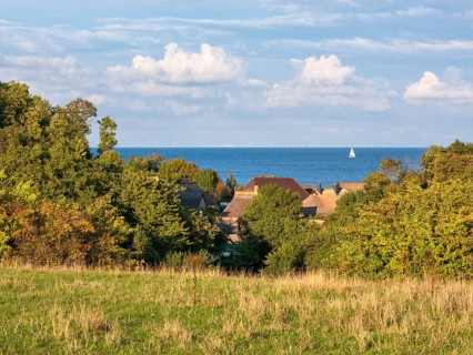 View over the thatched roofs of the fishing village of Vitt to the Baltic Sea, a sailboat on the