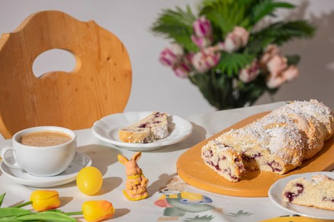 Breakfast table with coffee, sliced yeast braid and decoration for Easter