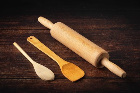Rolling pin and wooden utensils on a dark wooden table in a rustic atmosphere