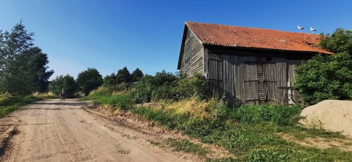 Rural scene with storks (ciconia) on a barn and a dusty dirt track, Masuria, Poland