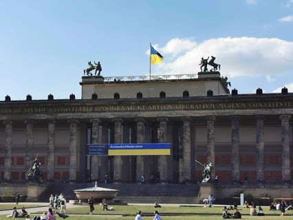 People relax on the lawn in front of the old museum on Museum Island in Berlin where the Ukrainian