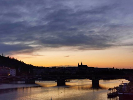 Dramatic orange sunset over the Vltava with silhouettes of Charles Bridge and Hradcany, Prague,