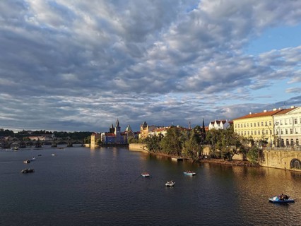Prague in the evening sun. Vltava surrounded by illuminated historic buildings, small boats