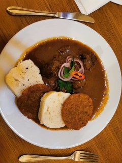Delicious dish, Czech goulash on a plate with bread dumplings, meat garnished in sauce and onions,