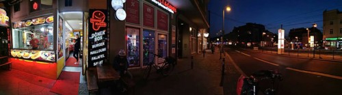 Panorama Lively evening street scene with illuminated snack bar and urban atmosphere, Pankow,