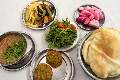 A table prepared with typical Egyptian street food of Fuul and Falafel with Salad, Pickles and