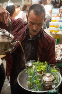 Tunis, Tunisia. 13th May 2024 A Tunisian man pours a glass of tradition mint tea in the busy