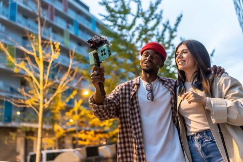 Diverse young couple vlogging urban exploration together, smiling and walking through the city