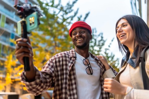 Diverse friends documenting moments with a smartphone on a gimbal stabilizer, recording content for