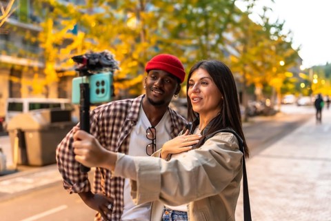 Diverse couple recording engaging video content on a smartphone with a gimbal stabilizer, producing