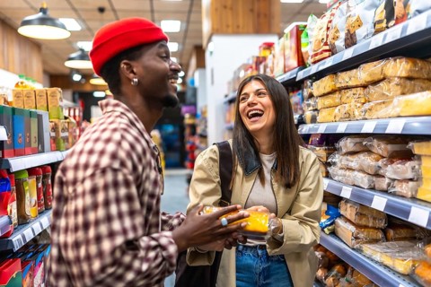 Happy young couple enjoying shopping together, smiling and talking in a store aisle while holding