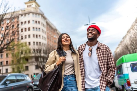 Happy multicultural couple walking together, smiling cheerfully while exploring the urban