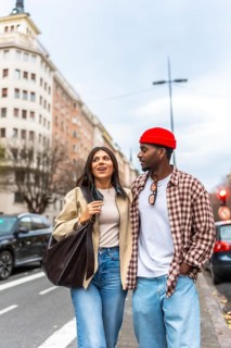 Young interracial couple walking arm in arm on a city street, smiling and talking as they enjoy