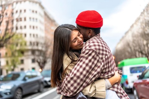 Young diverse couple embracing on an urban street, expressing love and affection, with a multi