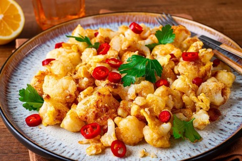 Spicy fried cauliflower served on a wooden countertop