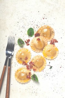 Fresh ravioli, with butter, spices and herbs, fried bacon, on the table, top view, light