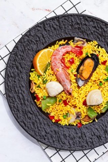 Seafood paella on a black plate, no people