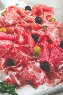 Assorted, meat appetizer, prosciutto, salami and ham, with olives, close-up, breakfast, top view,