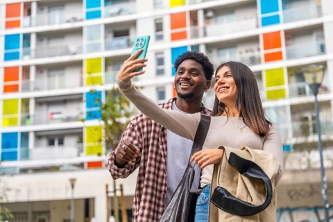 Happy young multiracial couple smiling, taking a selfie with a mobile phone in a vibrant urban