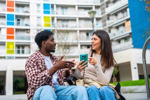 Diverse friendship bond as a young african american man and a young caucasian woman sit outdoors,