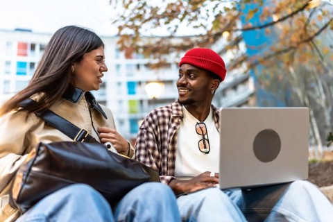 Diverse young students sitting outdoors in an urban environment, engaging in conversation and