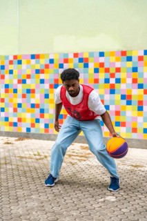 Young man dribbling a colorful basketball on a pavement court, showcasing an active street sport