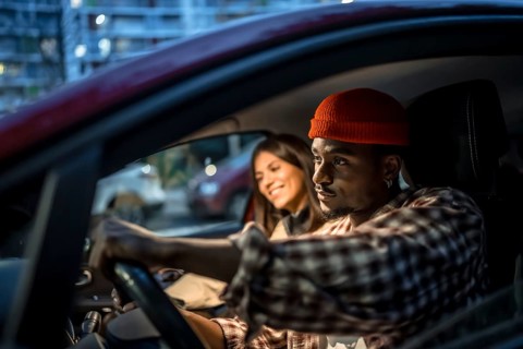 Young couple driving through city streets at night, enjoying a relaxed evening outing together