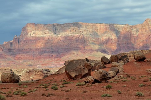 Large rocks spread across an impressive red desert landscape with dramatic skies, Grand Canyon