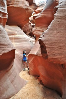 Girls in a narrow part of a sandstone canyon surrounded by bright orange rock walls, Antelope