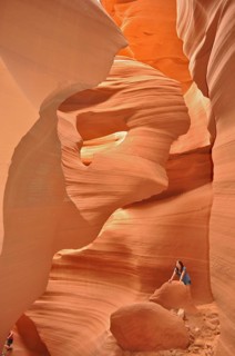 Rocky sandstone gorge in shades of orange with one person surrounded by smooth, lively rocks,