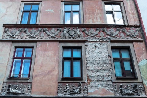 Relief band with cornucopias and figures on a dilapidated house façade from the 19th century,