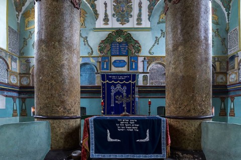 Columns of the central bima, a parish in the back, curtain in front of the Torah shrine, synagogue