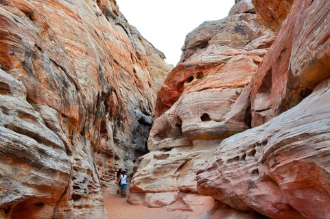 Narrow canyon with huge red rock walls and hikers, Valley of Fire State Park, Nevada, USA