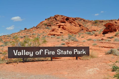 Valley of Fire State Park sign against a red rocky landscape under a blue sky, Valley of Fire State