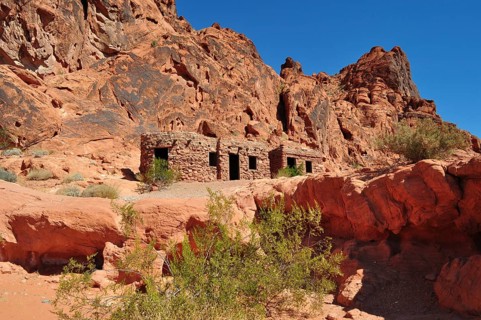 Abandoned stone houses nestled in a red rocky landscape under clear skies, Valley of Fire State