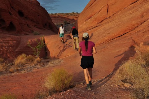 Group of hikers on a trail between red rocks in the desert, Valley of Fire State Park, Nevada, USA