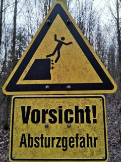Yellow warning sign in the forest with an indication of the risk of falling, quarry, Frankenwald