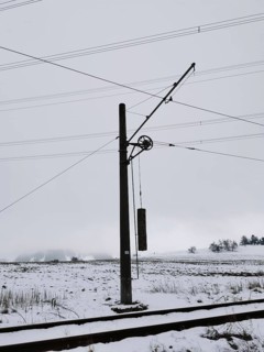 Snow-covered landscape with power pole and power lines on snow-covered railway tracks, Thuringian