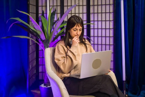 Young woman focused at a laptop in a modern studio, planning and creating social media and podcast