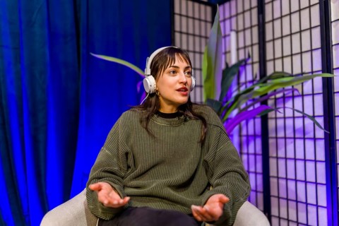 Woman wearing headphones and gesturing while speaking, creating engaging audio content for social