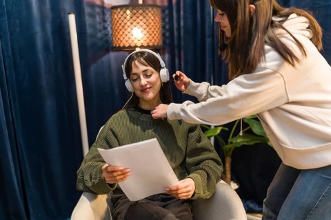 Content creator preparing for podcast recording in a professional studio, wearing headphones and