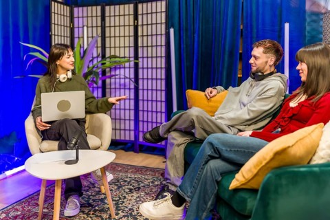 Young diverse creators recording a podcast in a stylish studio, chatting around microphones and