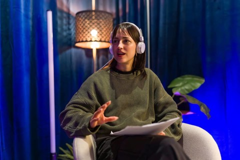 Young woman recording social media content or a podcast episode, wearing headphones and holding