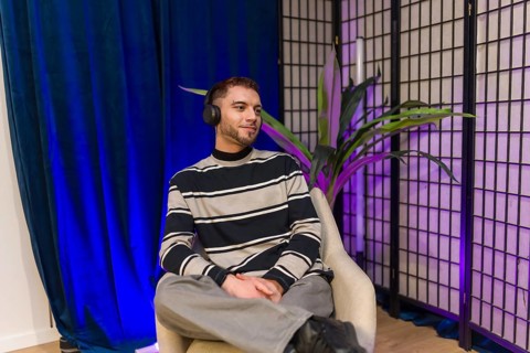 Young content creator wearing headphones, sitting in a modern studio setup, preparing for a podcast