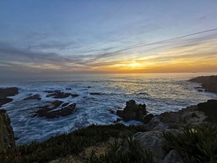 A peaceful sunset over the moving sea with intense colors in the sky, hiking on the Fisherman's