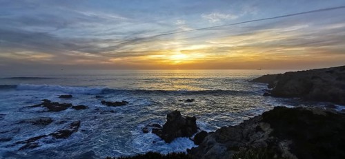A breathtaking sunset over the sea with dramatic waves and rocks, hiking the Fisherman's Trail,