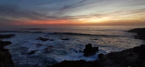 Subdued sunset with dark clouds and rocks in the sea, romantic atmosphere, hiking on the